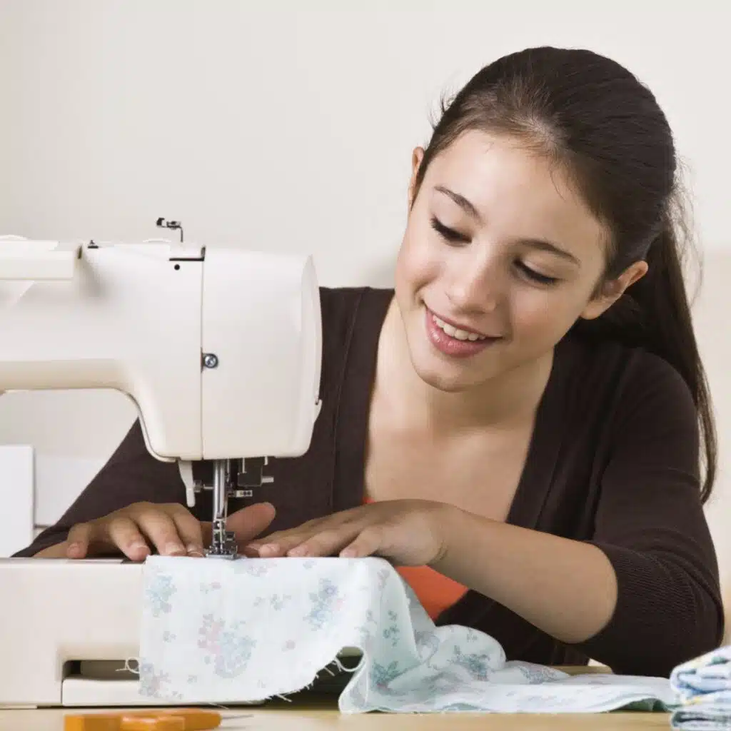 young girl at a sewing machine learning how to sew.