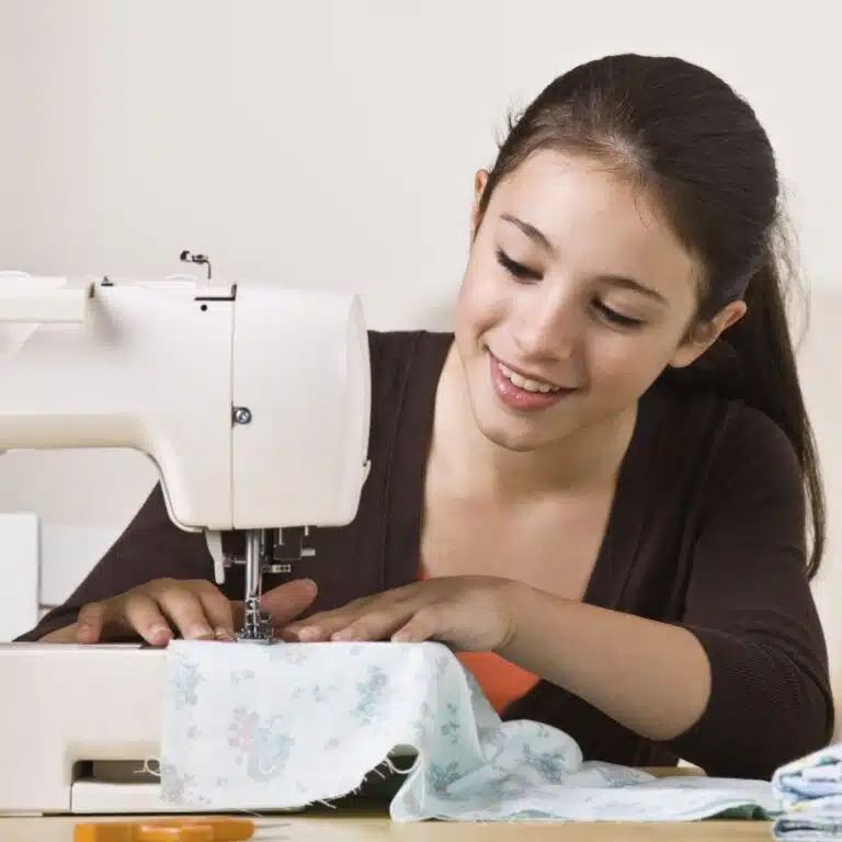 young girl at a sewing machine learning how to sew.